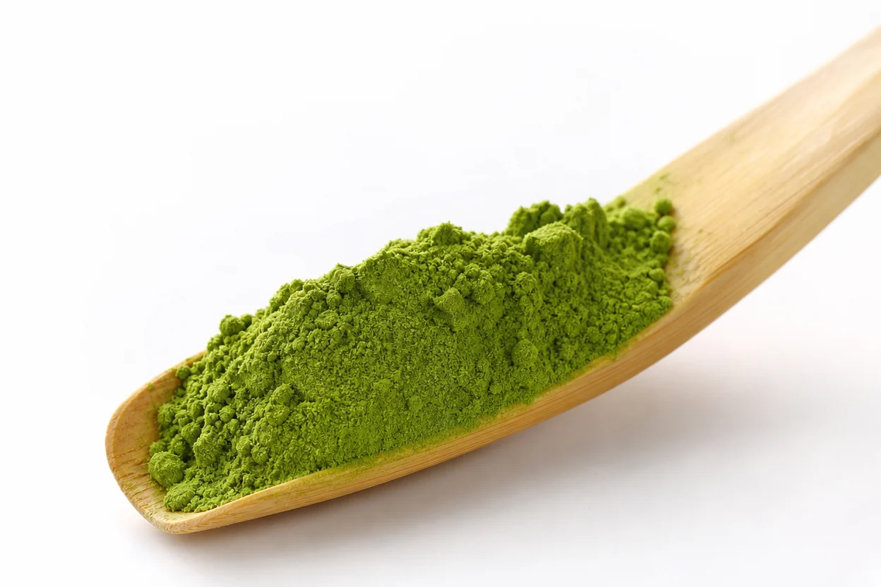 Ceremonial grade matcha powder in traditional bamboo scoop with tea bowl