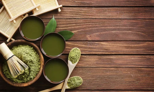 Fresh, vibrant green matcha powder in a tin next to a bamboo whisk, illustrating the shelf life of matcha.